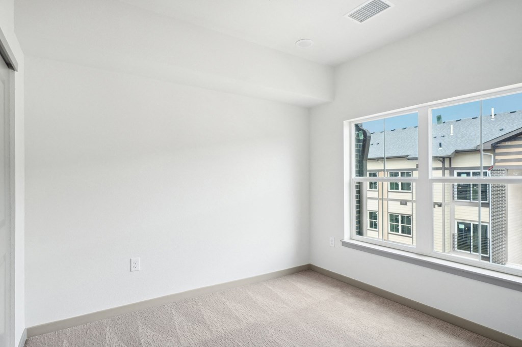 a bedroom with a large window and white walls