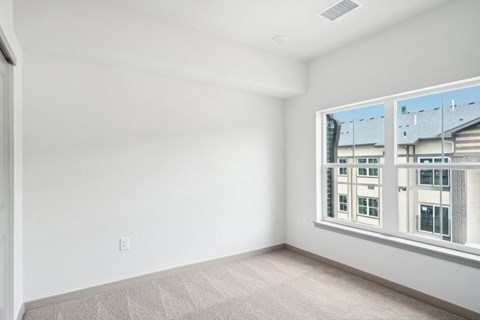 a bedroom with a large window and white walls