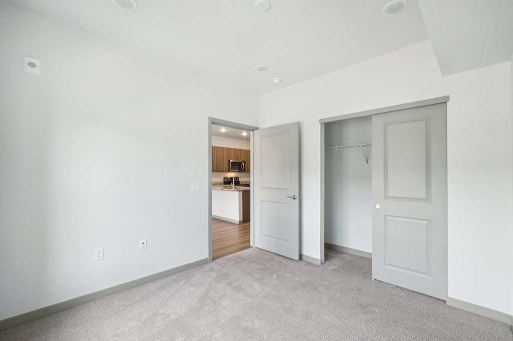 a living room with white walls and a door to a kitchen