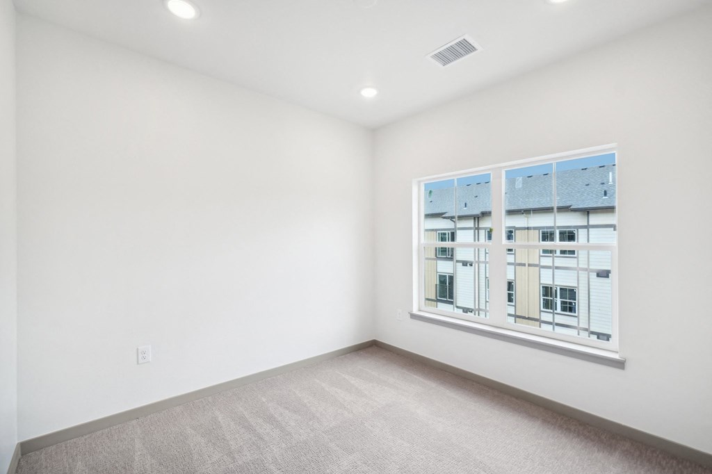 a bedroom with a large window and a carpeted floor