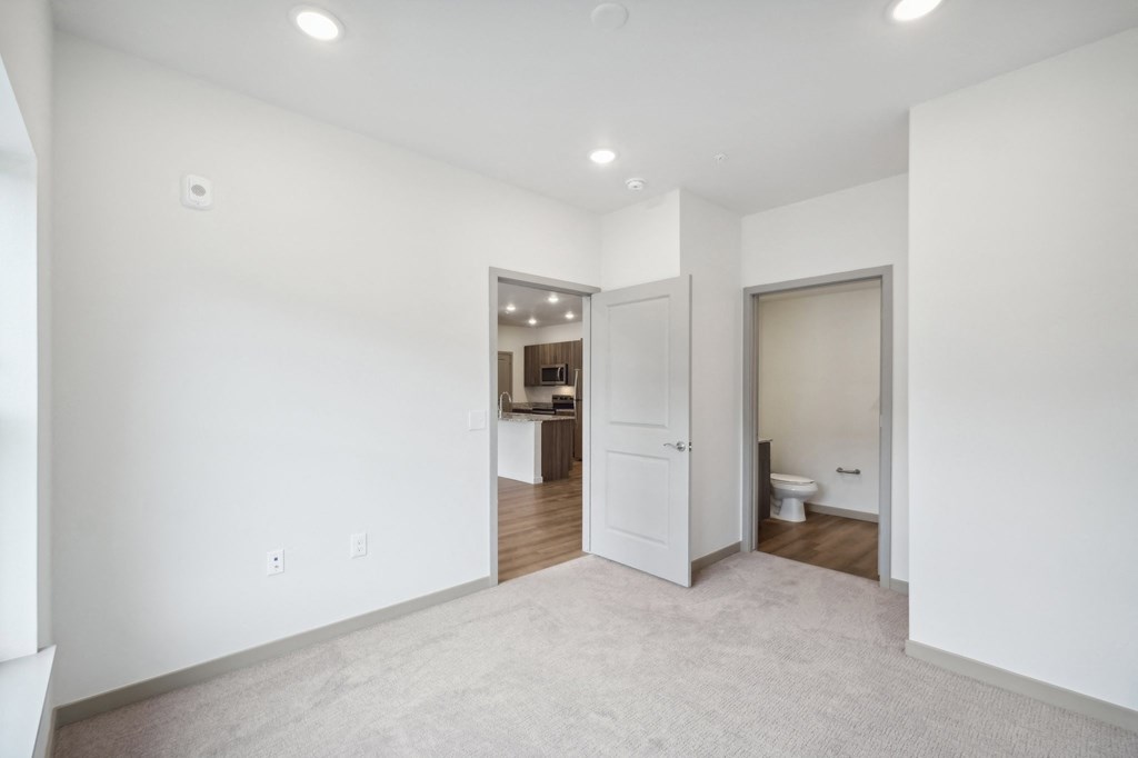 a living room with white walls and a door to a bathroom