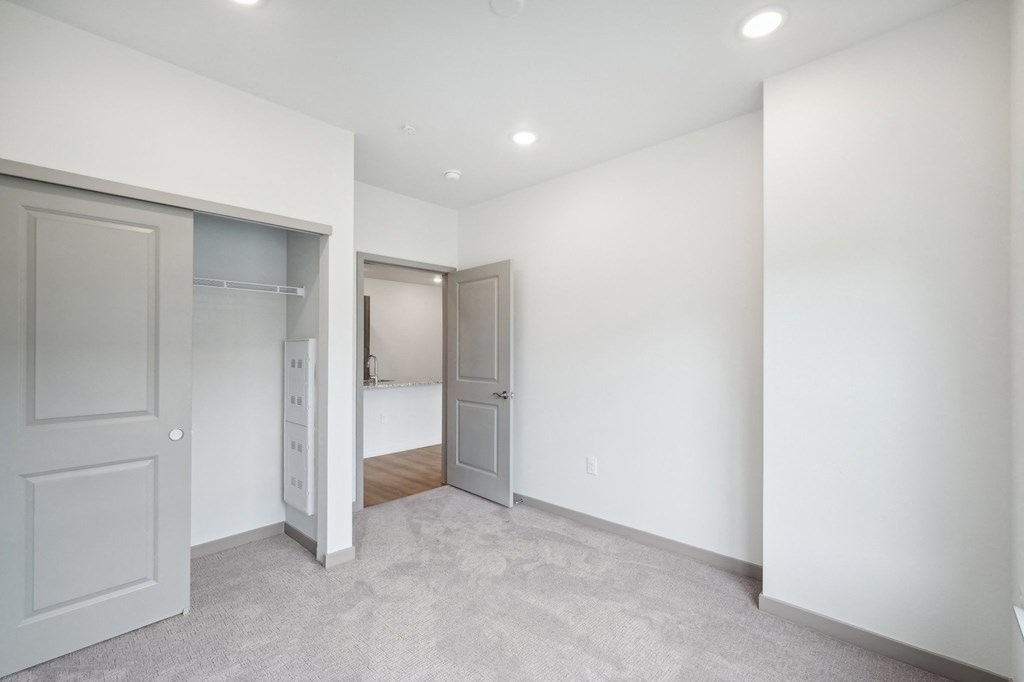 a bedroom with white walls and a door to a closet