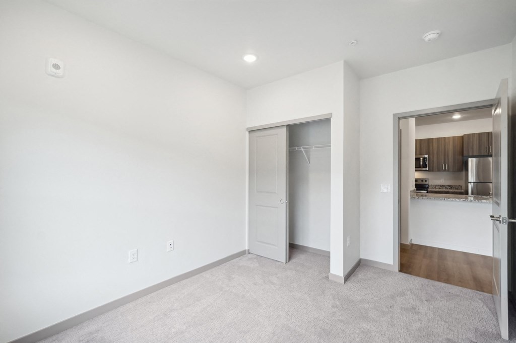 a living room with a white wall and a door to a kitchen