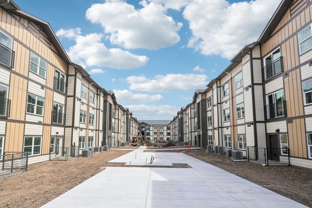 an empty street in front of a row of new apartment buildings