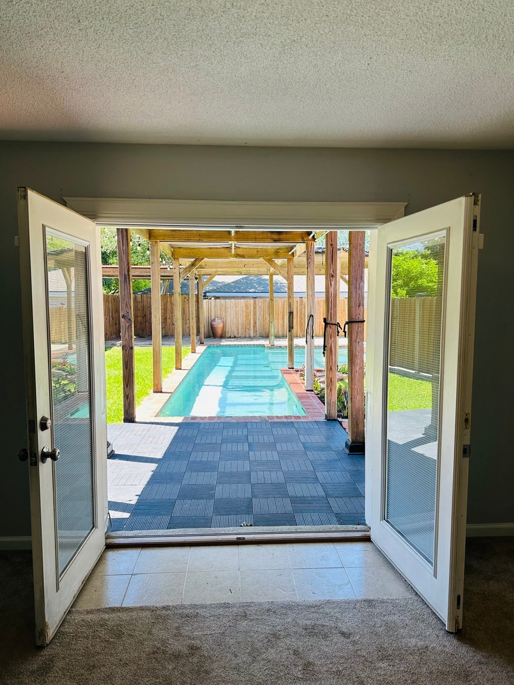 a view of a pool from a room with open doors
