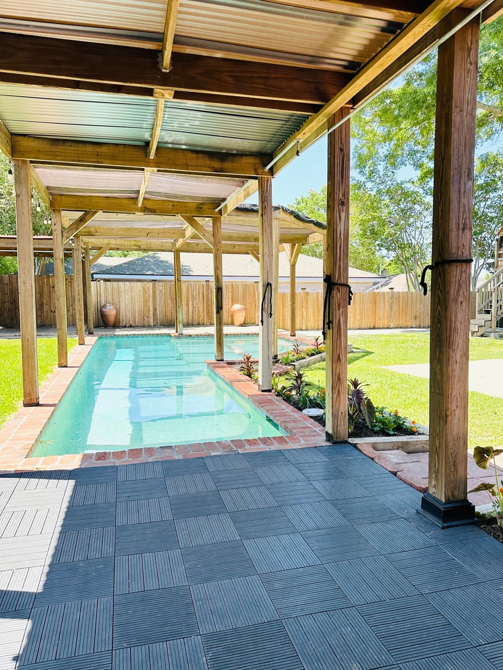 the pool is under a covered porch with wood beams