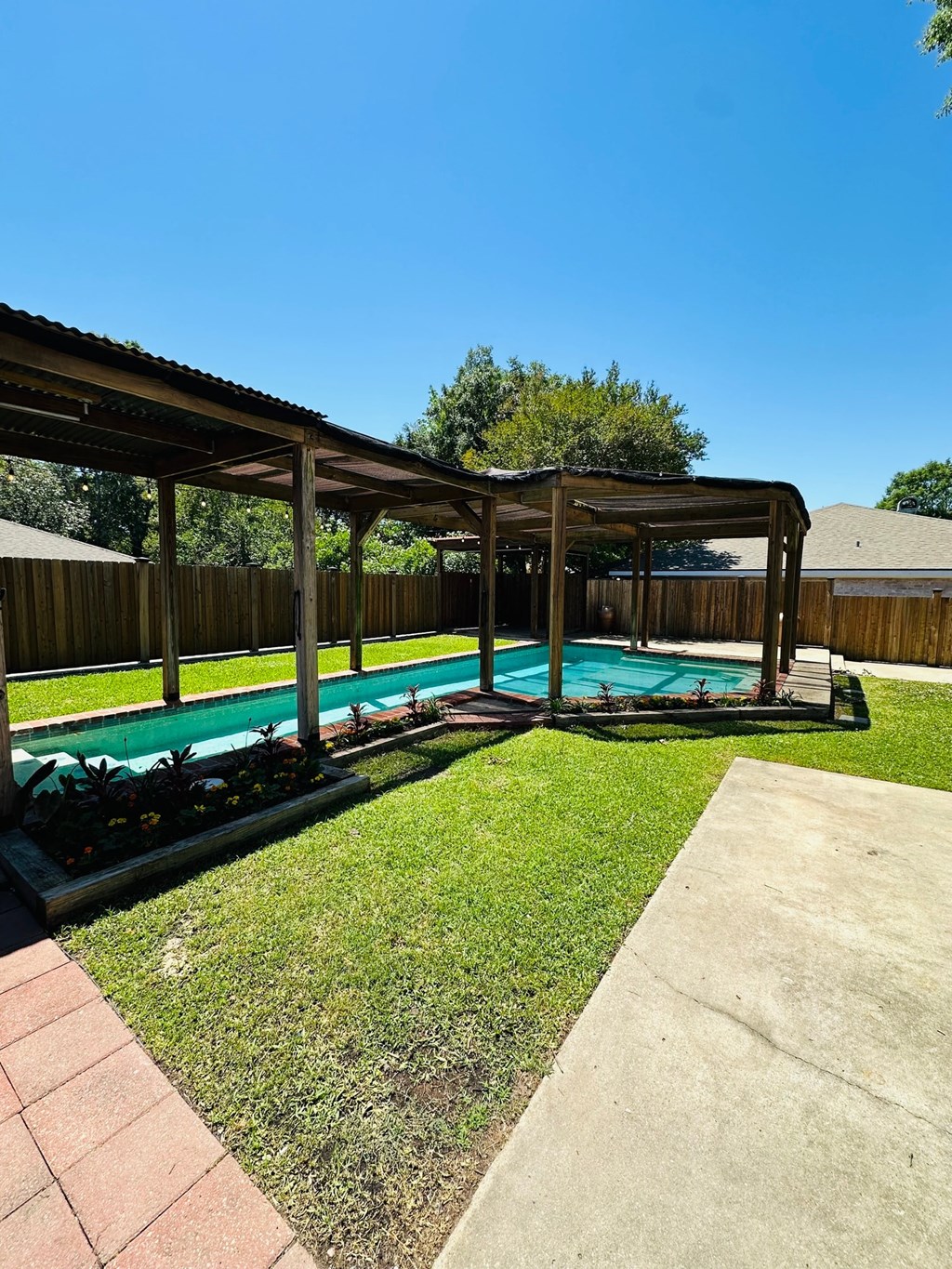 a backyard with a swimming pool and a covered patio