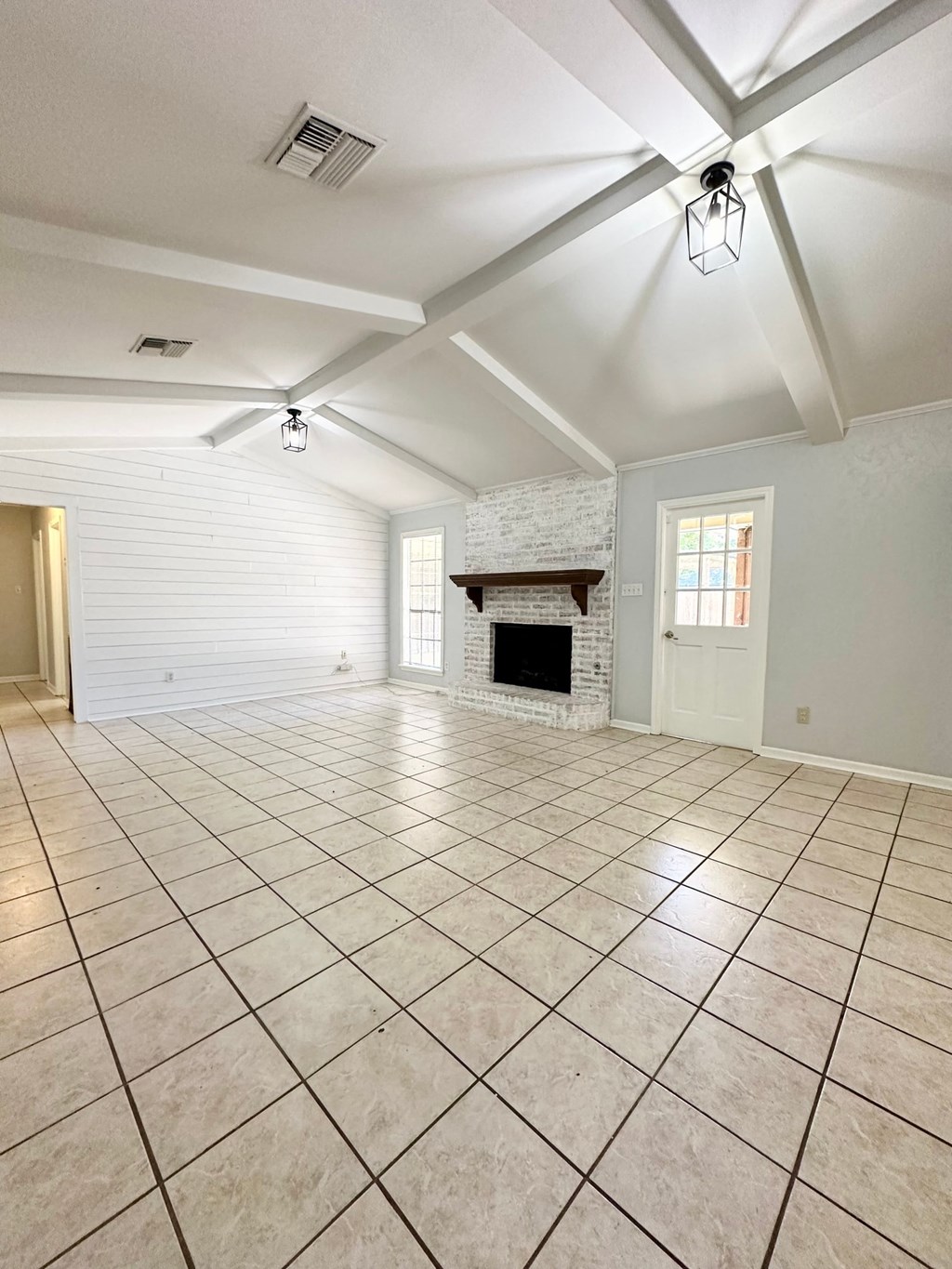 an empty living room with a fireplace and tile flooring