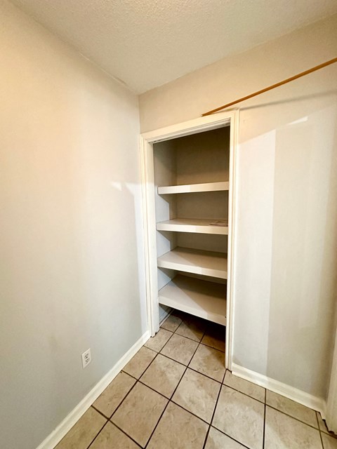 an empty closet in an empty room with a tiled floor