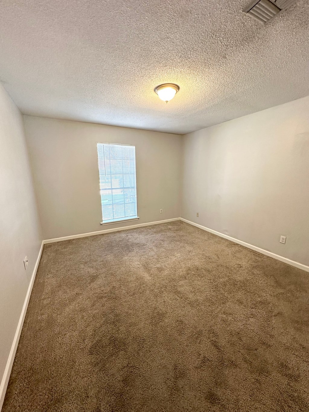 an empty room with carpet and a window