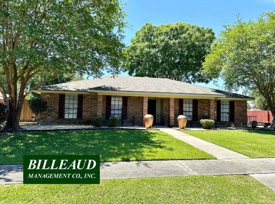 a small brick house with a lawn and trees