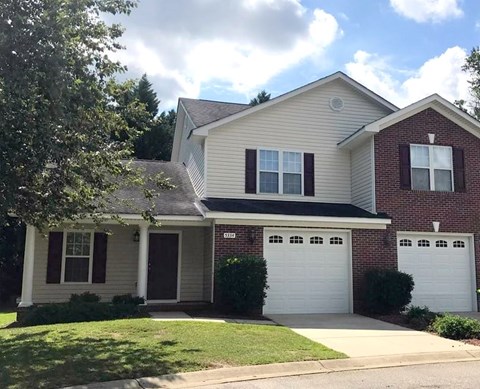 A two-story house with a garage door and a driveway.