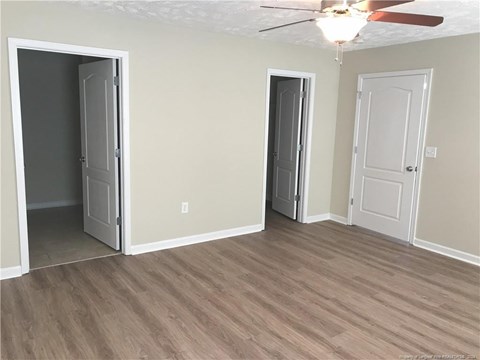 A room with a ceiling fan and three doors.