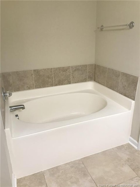 A white bathtub with a silver faucet and a silver shower rod.