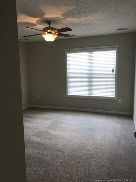 A room with a ceiling fan and a window with blinds.