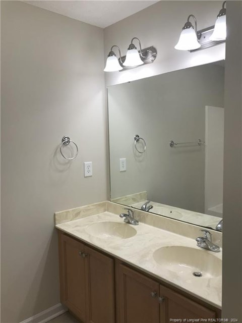 A bathroom with a double sink vanity and lights above it.