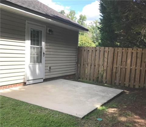 A small house with a white door and a wooden fence.