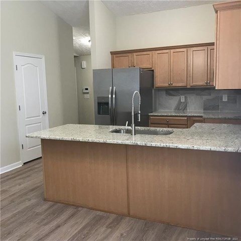 A kitchen with a granite countertop and wooden cabinets.