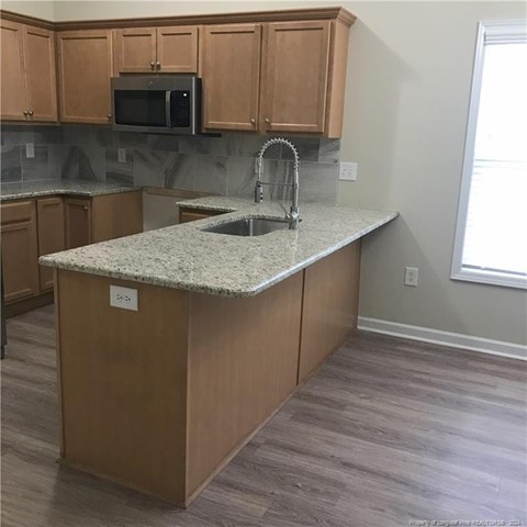 A kitchen with a granite countertop and wooden cabinets.