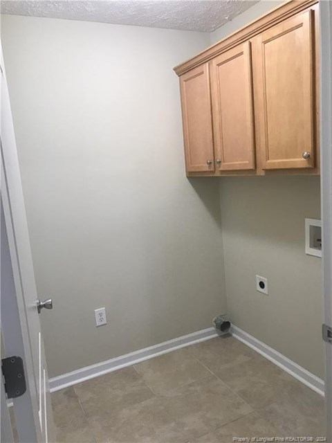 A room with a white wall and a brown cabinet.