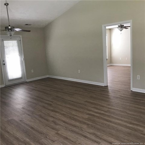 A room with wood flooring and two ceiling fans.