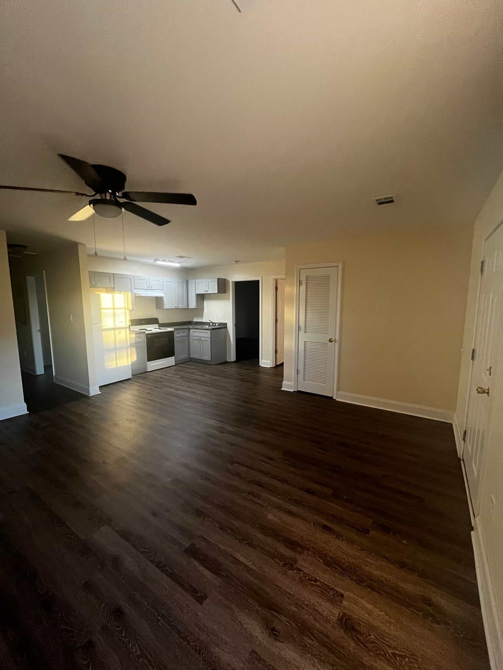A room with a ceiling fan and wooden flooring.