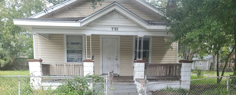a yellow house with a white door and a fence