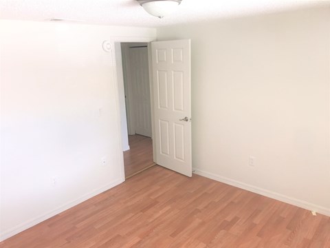 a bedroom with a wooden floor and a white door