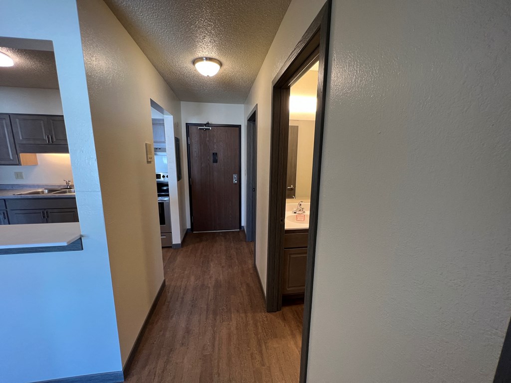 a hallway with a door to a bathroom and a kitchen