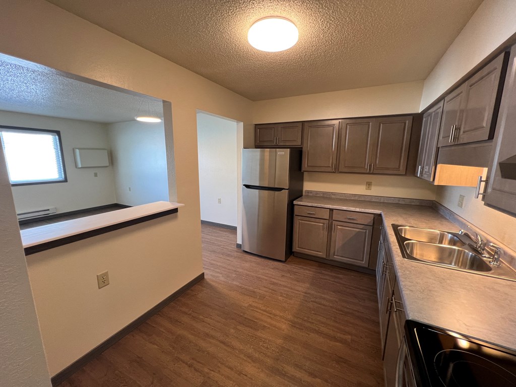 an empty kitchen with stainless steel appliances and wooden floors