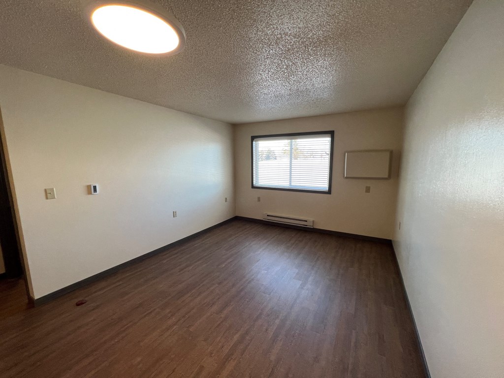 an empty living room with wood floors and a window