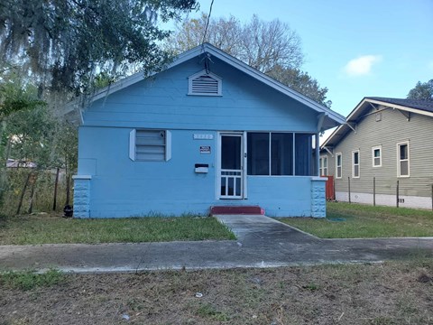 a blue house with a sidewalk in front of it