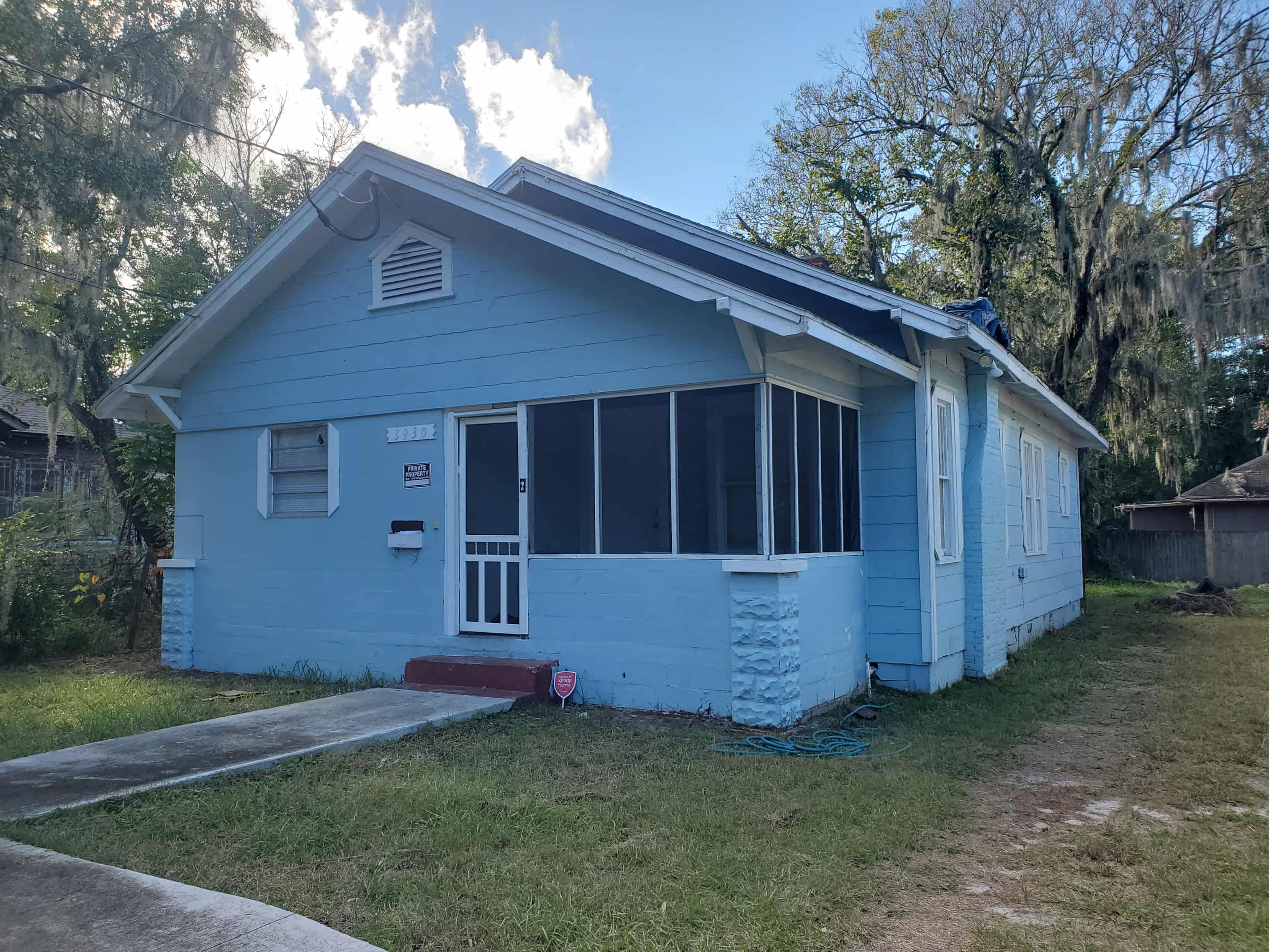 a blue house with a roof on the side of a street