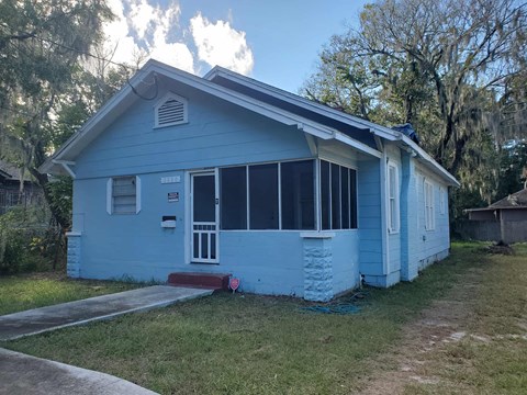 a blue house with a roof on the side of a street