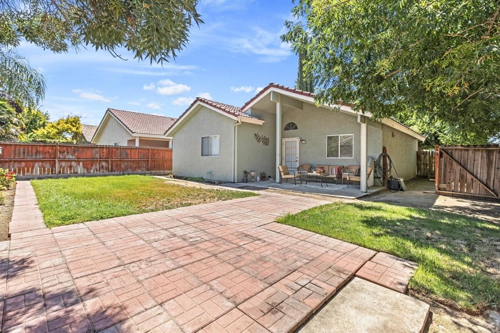 the backyard of a house with a brick patio and a fence