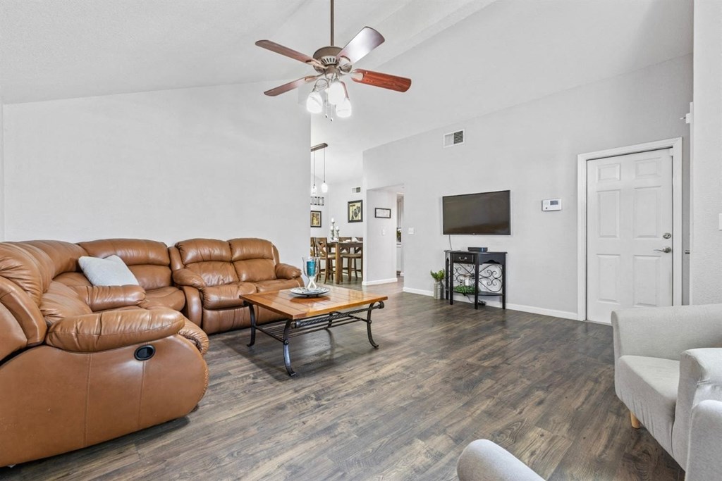 a living room with leather furniture and a ceiling fan