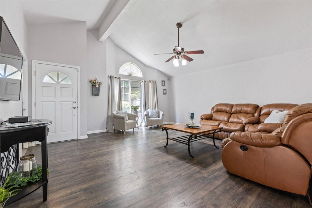 a living room with leather furniture and a ceiling fan