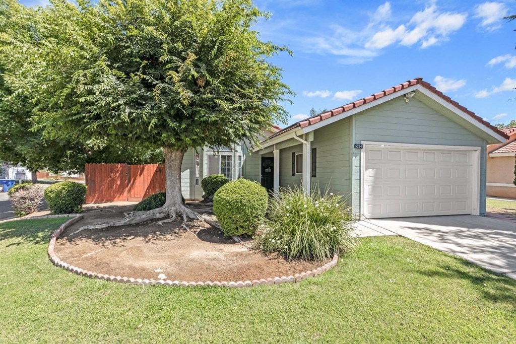 a house with a garage and a tree in front of it