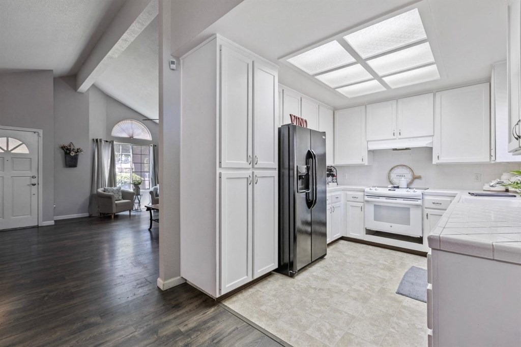 a white kitchen with white cabinets and a refrigerator