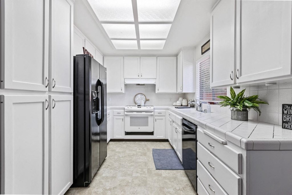 a white kitchen with white cabinets and a black refrigerator