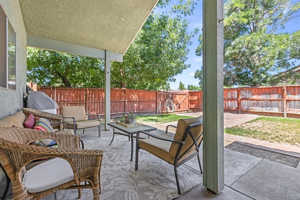 a covered patio with chairs and a table in a backyard