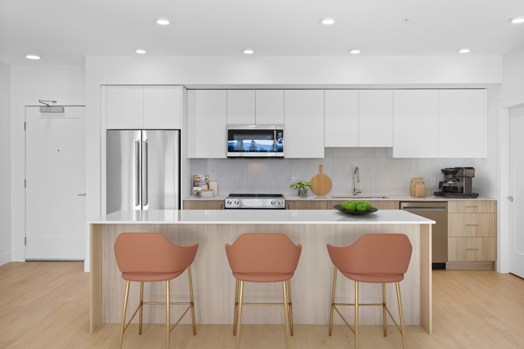 A modern kitchen with a white color scheme and a central island with three chairs.