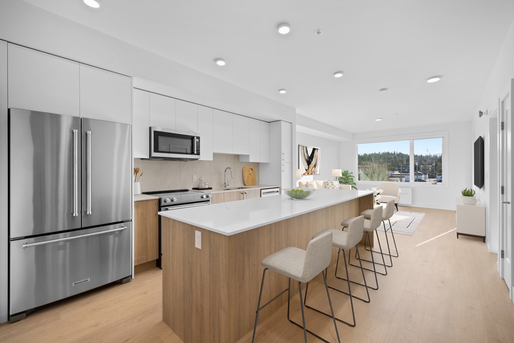A modern kitchen with a refrigerator, stove, and bar stools.