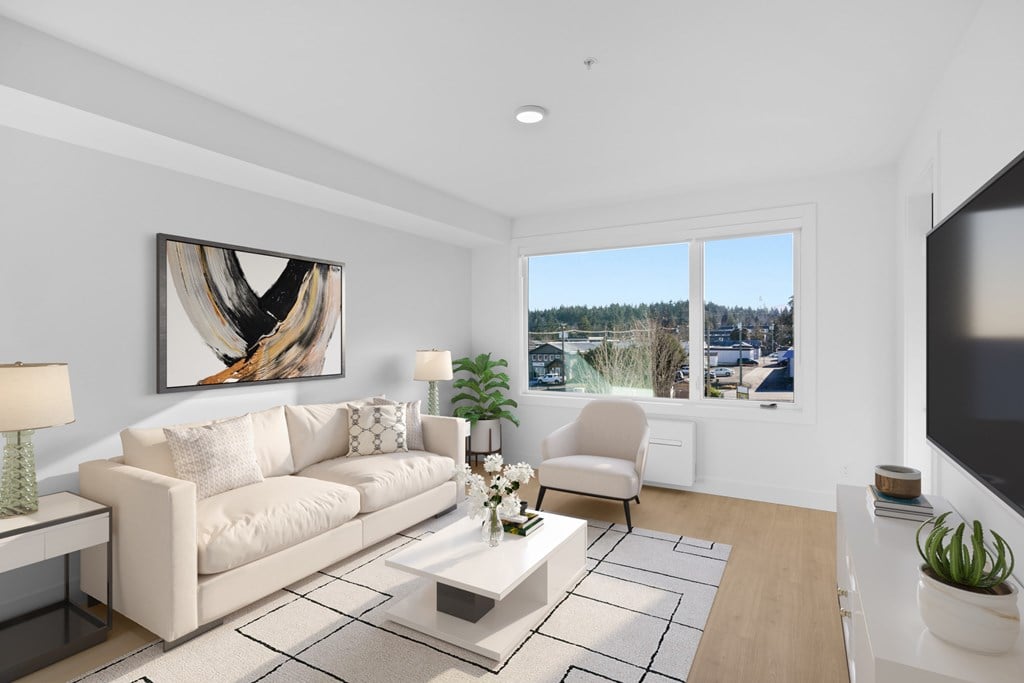 A modern living room with a large painting on the wall and a view of the outdoors through the windows.