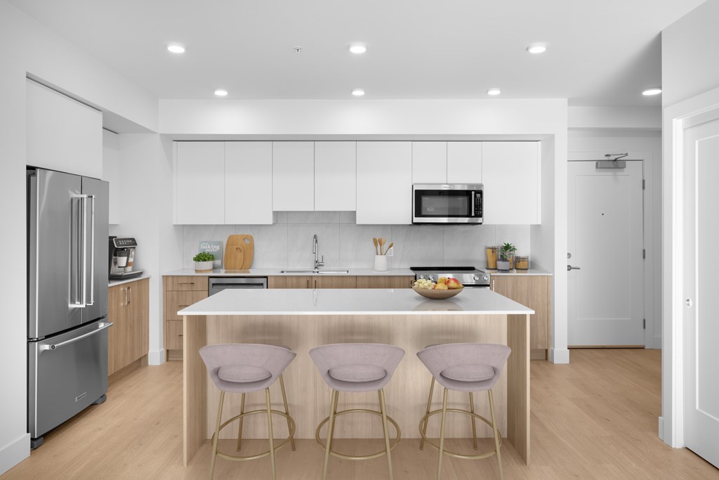 A modern kitchen with a white countertop and bar stools.