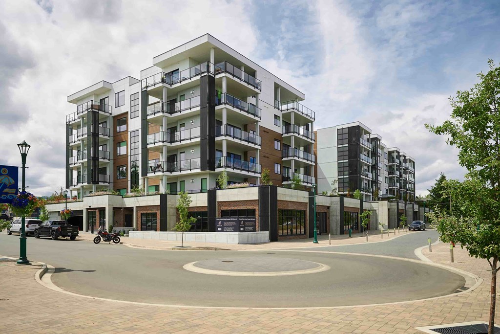 A roundabout in front of apartment buildings with a motorcycle and cars on it.