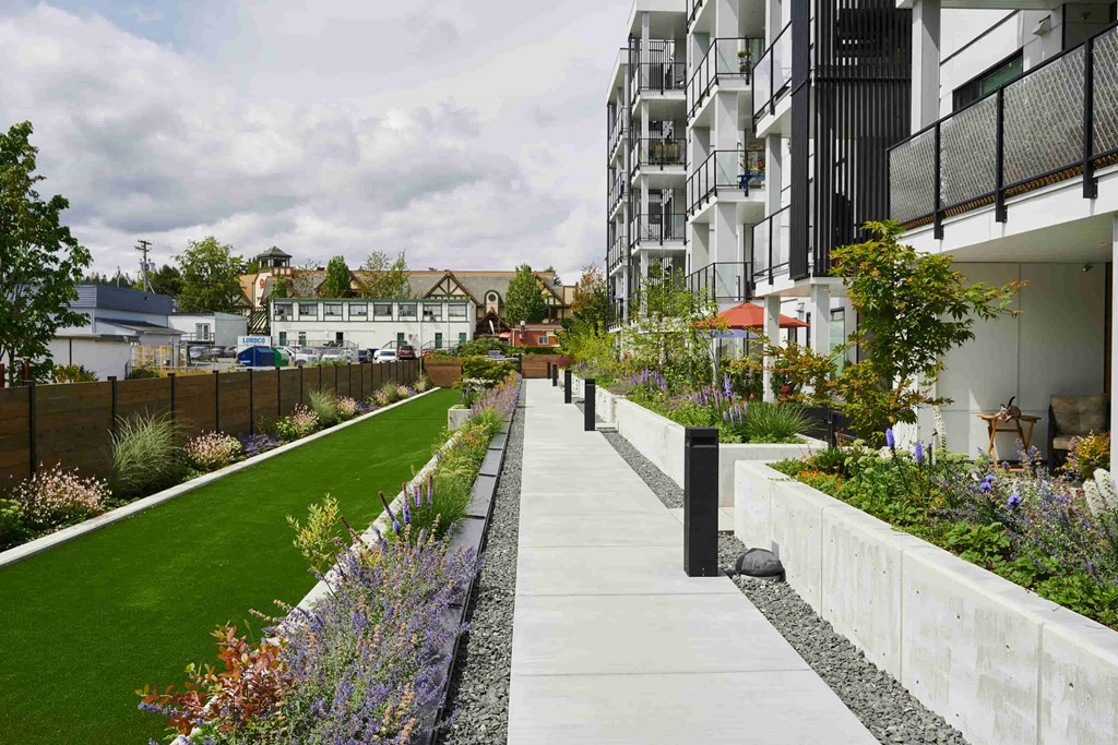 A long concrete walkway with a grassy area on the left and a building on the right.