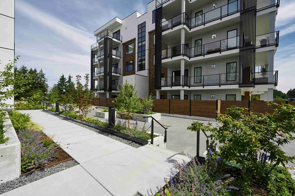 A modern apartment building with a walkway in front of it.