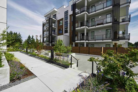 A modern apartment building with a walkway in front of it.