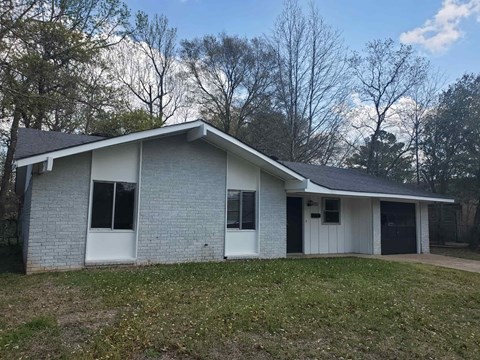 A house with a grey brick exterior and a white door.
